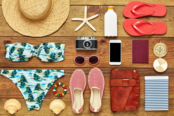 Full frame shot of summer vacation accessories. Directly above shot of travel and beach equipment flat lay. They are arranged on wooden floor.