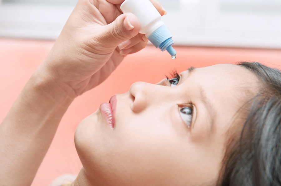 close up mother applying eye drops to her daughter because of eye irritation