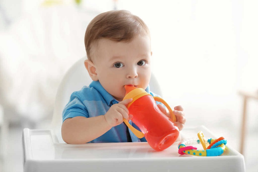 Cute baby drinking water indoors