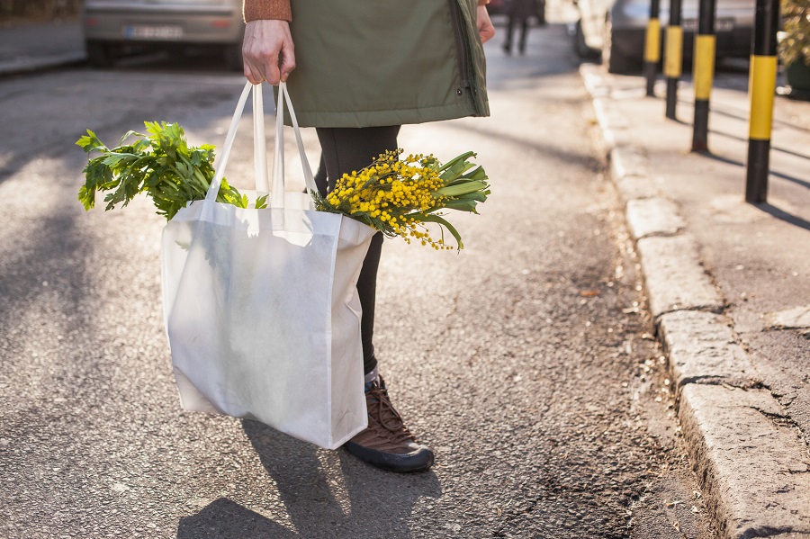 Woman is holding a bag full of fresh early spring vegetables.