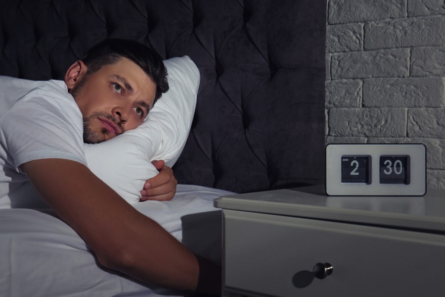 Man suffering from insomnia in bed at home