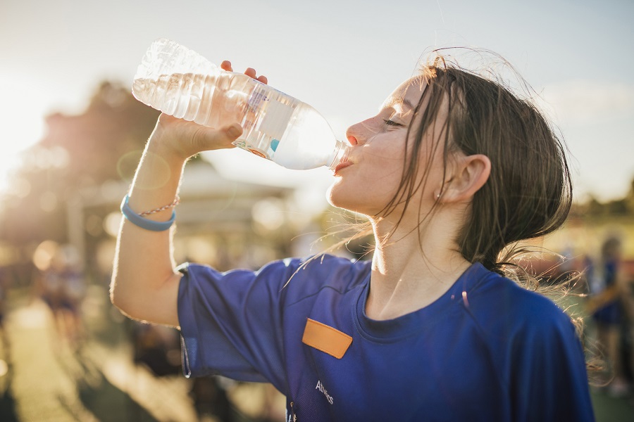 Little girl is taking a big gulp of water from a bottle during athletics club.