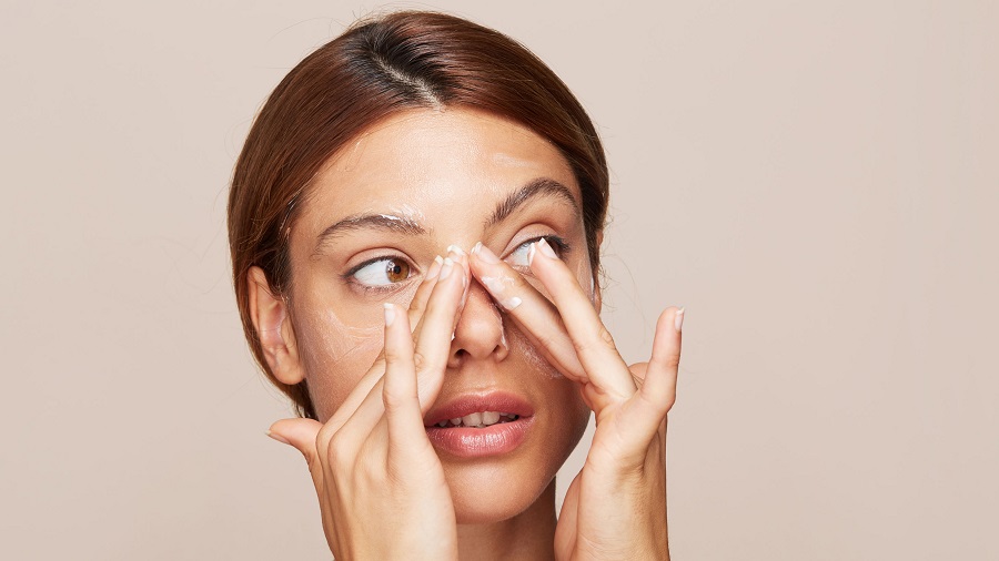 Beautiful woman applying facial skin lotion moisturiser