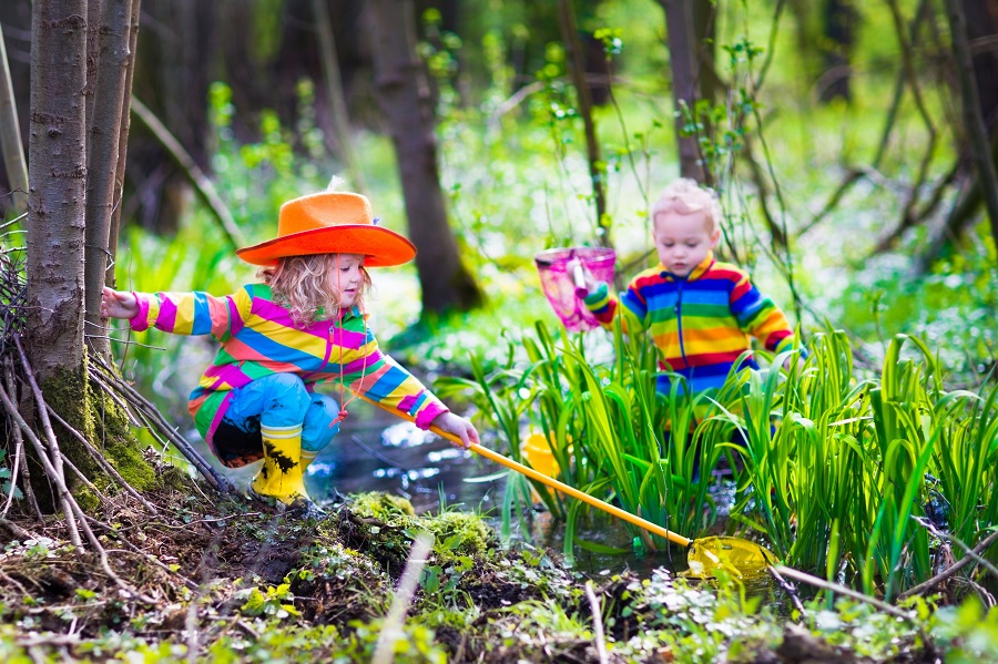 Children playing outdoors catching frog